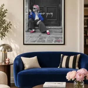 Forever Young print, 30 × 40 inch, black frame above a curved cobalt-blue sofa