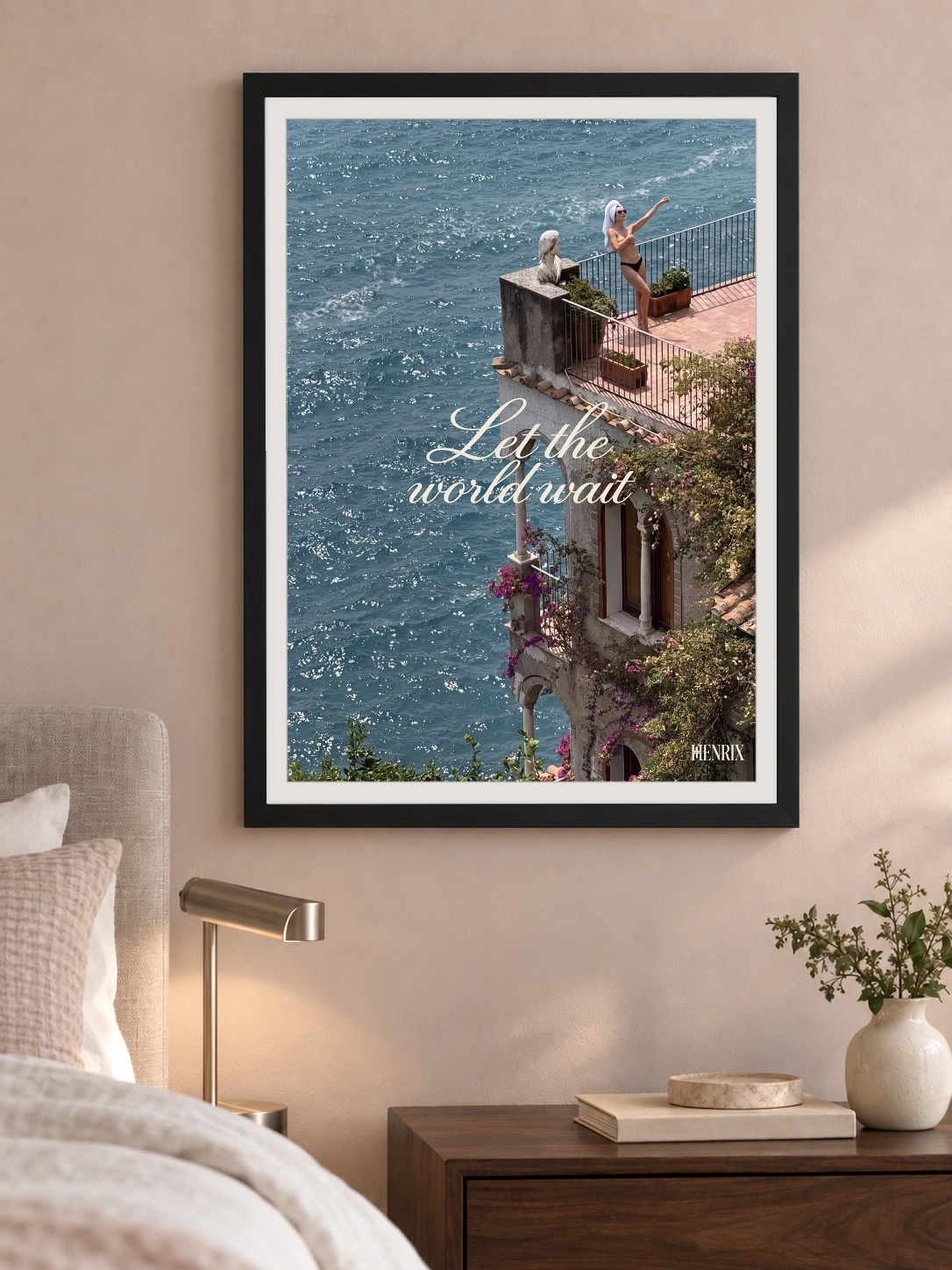 Let the World Wait print, 18 × 24 inch, black frame on a bedroom wall beside a brass lamp