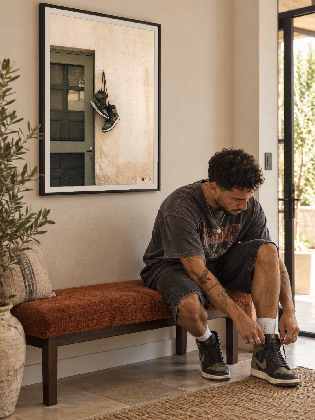 Home at Last print, 18 × 24 inch, black frame on a hallway wall behind a seated man tying his sneakers