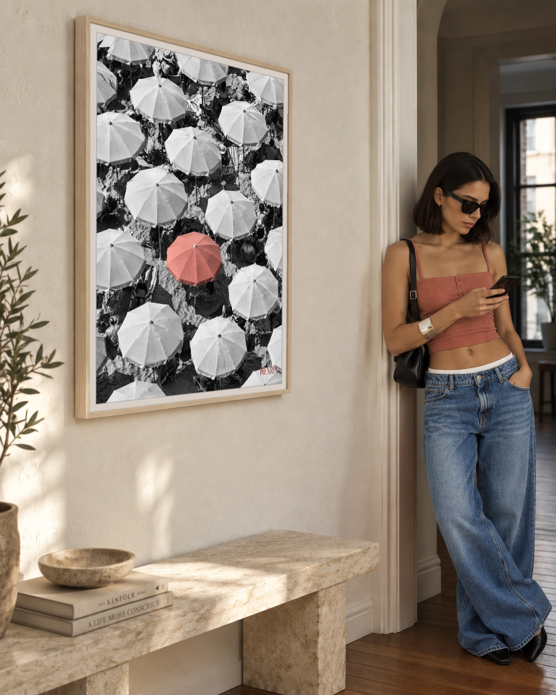You Were Never Meant to Blend In print, 30 × 40 inch, Natural Wood frame beside a woman in a coral top and jeans checking her phone