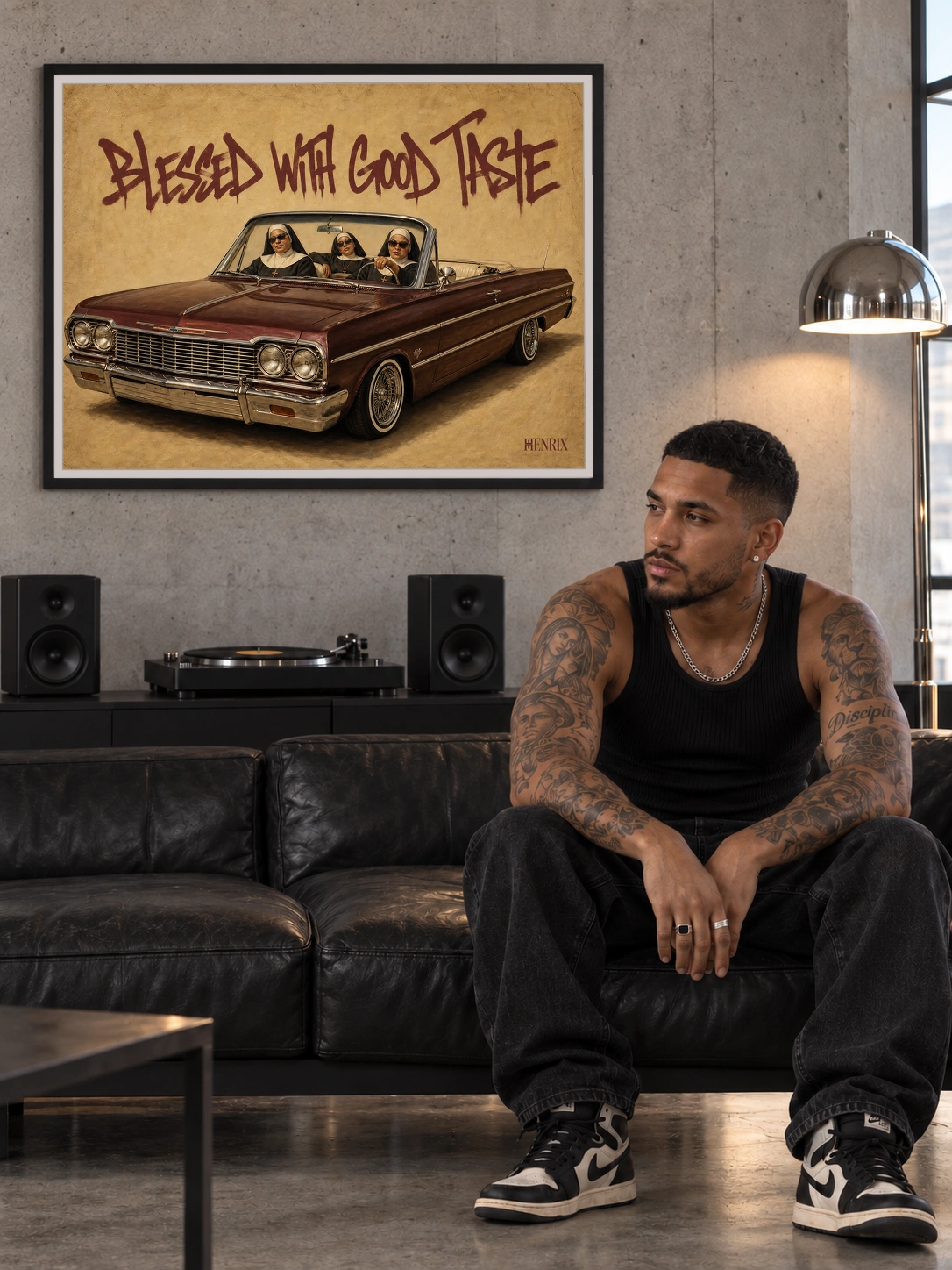 Blessed With Good Taste print, 48 × 36 inch, black frame behind a tattooed man seated on a leather sofa