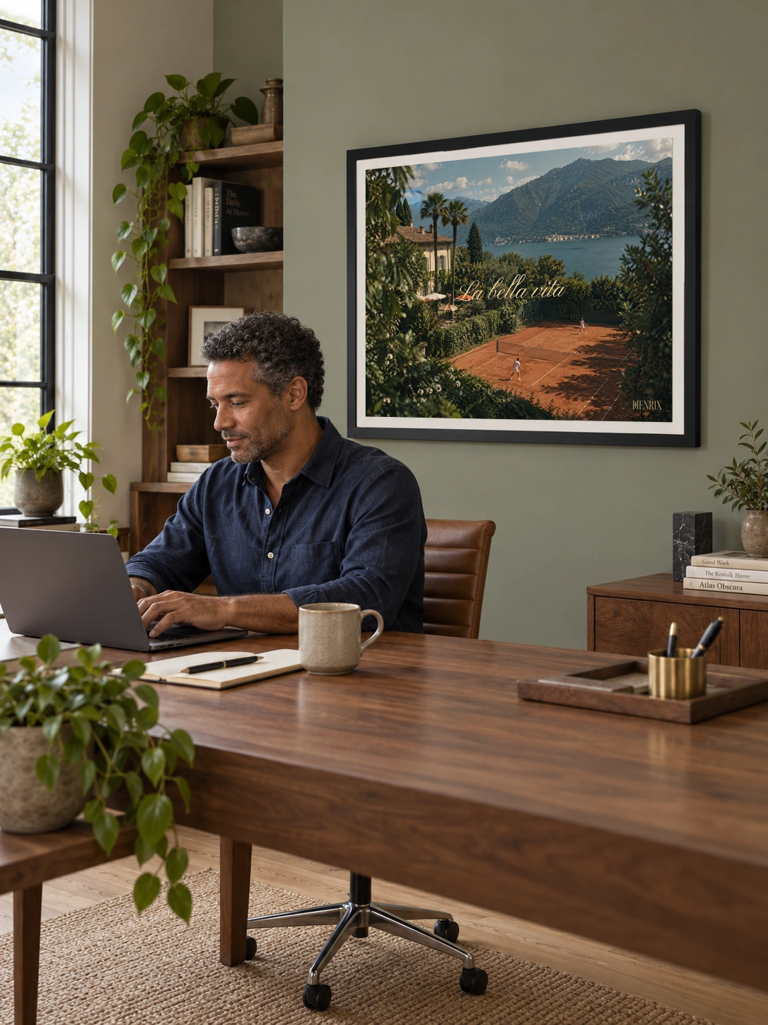 La Bella Vita print, 24 × 18 inch, black frame on an office wall behind a man working at a desk