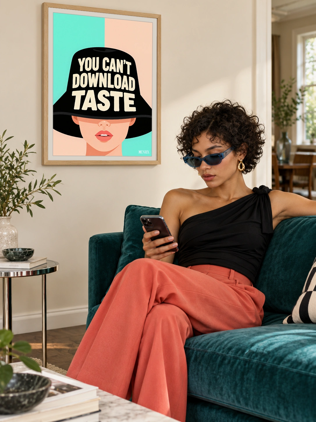 You Can't Download Taste print, 18 × 24 inch, Natural Wood frame behind a woman checking her phone on a teal sofa