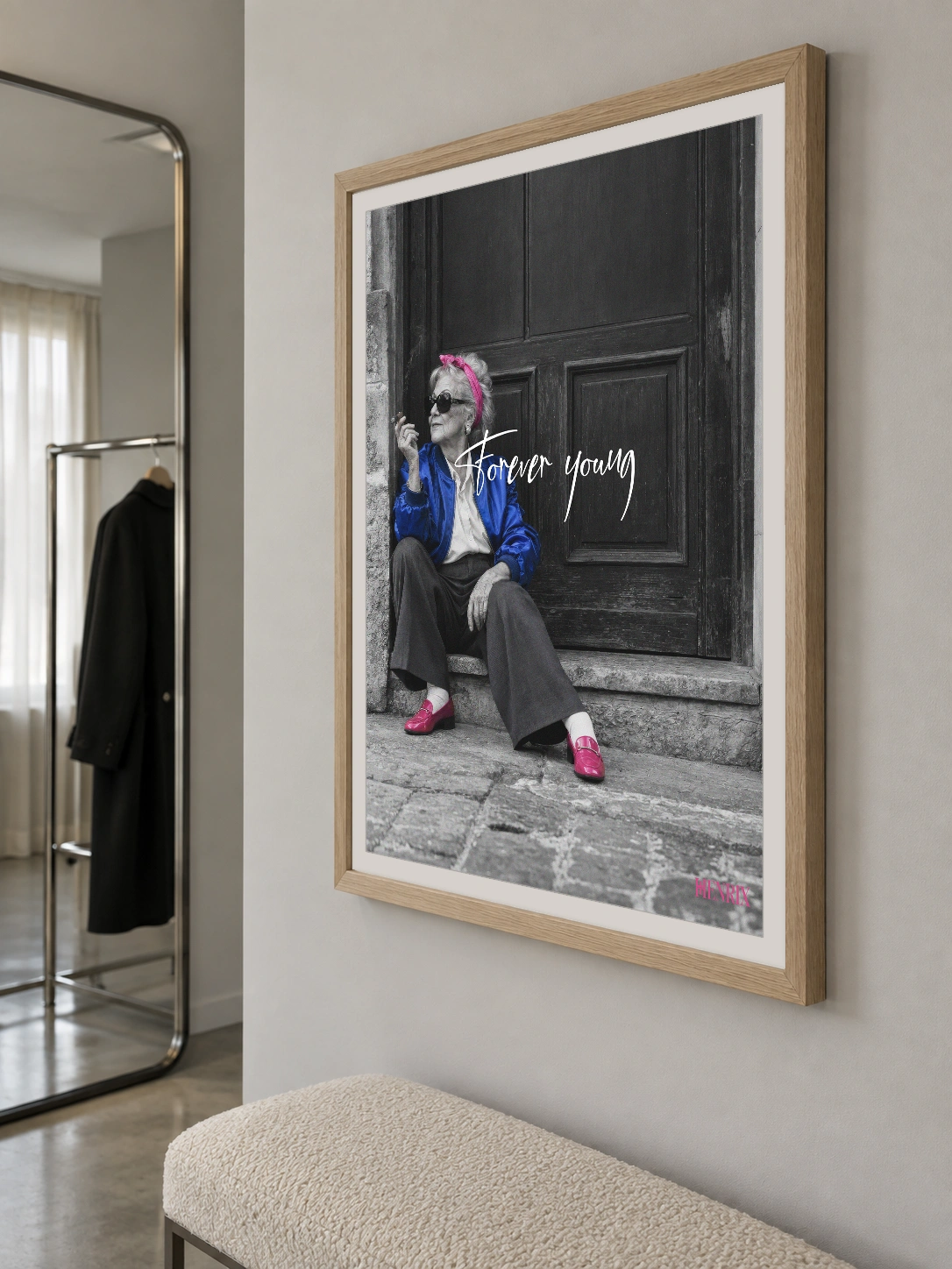 Forever Young print, 18 × 24 inch, Natural Wood frame above an entry bench near a mirror, viewed obliquely