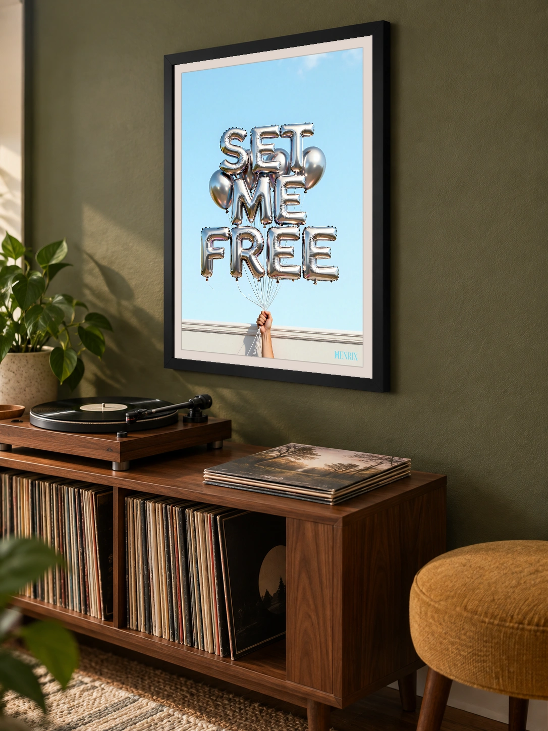 Set Me Free print, 18 × 24 inch, black frame above a record cabinet on an olive wall, viewed obliquely