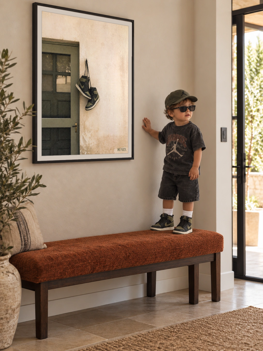 Home at Last print, 18 × 24 inch, black frame on a hallway wall beside a child in a cap and sunglasses standing on a bench